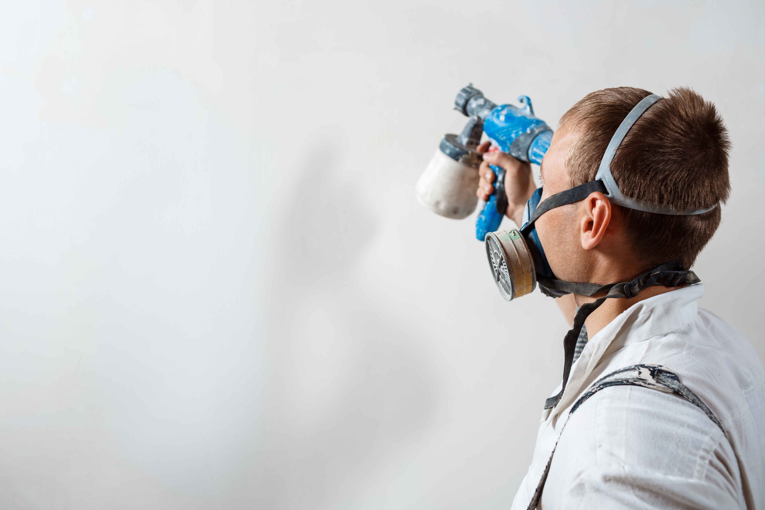 worker-painting-wall-with-spray-gun-white-color